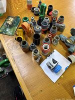 Top view of multiple plastic garden hose connectors and fittings, including some threaded and snap-on types, arranged on a wooden surface.