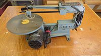 Overall side view of the vintage Delta scroll saw showing the motor, work table, and blade arm.