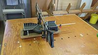 Front angle view of the vintage Hempe manual precision mitre saw showing the saw handle, angle guide, and wooden base.