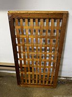Full view of the rectangular wooden lattice panel with a visible varnished wood frame and cross-grain lattice pattern inside.