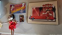 Photo showing the four Betty Boop themed items: plush doll, no smoking sign, small illustration, and framed artwork.