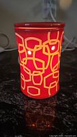 Image of the red ceramic electric wax warmer lit up showing the white geometric pattern illuminated.