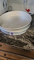 Two Wilton 12 inch round cake pans stacked showing brand label and size.