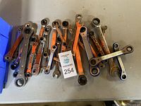 Top view of assorted ratchet wrenches spread out showing 26 pieces with metal and orange finishes.