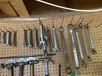 Wide shot showing assorted wrenches and hammers hanging on a pegboard.