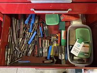 Drawer containing a variety of metal taps and dies, some in plastic tubes or boxes, various sizes and types visible.