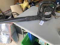 Full view of Black & Decker leaf blower/vacuum on a table in garage showing overall design and housing.