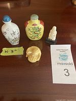 Four items shown: two Chinese snuff bottles and two small Asian figurines.