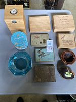 Overview of the lot showing various antique wooden cigar and tobacco boxes, two ashtrays (blue glass and brown ceramic), a Player's tobacco tin, and a standing humidor with round hygrometer.