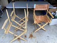 Three wooden director's chairs, two missing canvas seats and backs, one chair complete with canvas showing wear and stains.