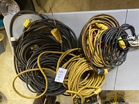 Top view of multiple coiled electrical cords in black and yellow, including connectors.