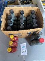 Box of twelve gray bottles with red caps of GUNK Lead Substitute, along with four red bottles with yellow caps of BARDAHL Insted O'Lead bottles, all on a table.