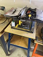Full view of the Mastercraft 10 inch bench saw mounted on its stand, with user manual and tools placed on top.
