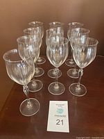 Set of 10 clear Mikasa Spring Petals white wine glasses on a wooden surface, arranged in two rows.
