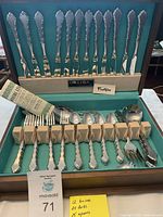 Overview of cutlery pieces arranged in wooden box showing knives vertically set in top slot, forks and spoons below, and other utensils on the right.