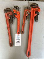 Four orange RIDGID pipe wrenches laid flat, showing range of sizes and general condition.