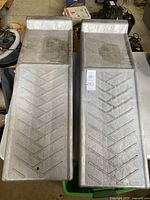 Top view of both plastic car ramps showing length, raised back edges, chevron tread pattern and dirt marks.