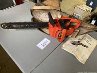 Remington Mighty-Mite 500 chainsaw laid on a table with its canvas carrying case and user manuals visible.