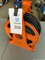 Side view of orange reel with rollout extension cord wound on it, showing the winding handle