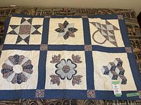 Full view of handmade quilt showing distinct pattern blocks in blue and cream colors on a couch