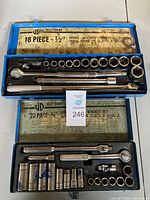 Overview of two blue metal Westward socket wrench sets, one 18-piece 1/2" drive and one 20-piece 3/8" drive, opened showing contents inside organized in slots.