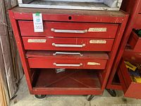 Front view of red rolling tool chest showing three drawers with labels and an open bottom compartment.