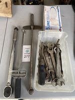 Full view of torque wrenches, long wrench, screwdriver, and container with assorted wrenches on table