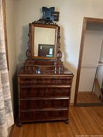Front view of vintage dresser with ornate mirror and dark polished wood, showing turned side columns and carved legs.