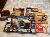 Photo of entire lot spread on bed including domino sets, card decks, chess books, Rummikub and Play Tray games