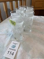 Seven clear vintage glasses with a frosted etched starburst design arranged on a cloth surface, with a size label showing 5 1/2 inches.
