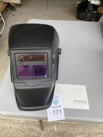 Front view of the black auto darkening welding helmet showing the viewing window and purple tinted lens.