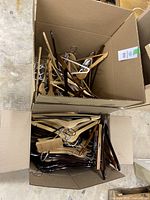 Top view of two cardboard boxes filled with assorted wooden hangers in various finishes showing quantity and style variety.