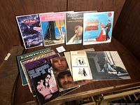 Photo showing 8 vinyl records from various artists in a wooden shelf, includes albums by The Osmonds, Carole King, Lawrence Welk, and orchestral groups
