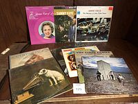 Photo of multiple vintage vinyl records standing upright including albums by The Marian Voice of L.M., Sammy Kaye, Semper Fidelis, and others.