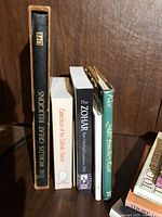 Photo shows five standing books on religions with visible titles including The World's Great Religions by LIFE, Catechism of the Catholic Church, The Zohar, Light From the Ancient East, and The Thora Leviyathen.