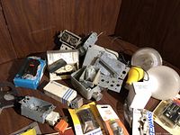 Top view of assorted electrical switches, fixtures, mounting boxes, and packaged hardware on a wooden surface