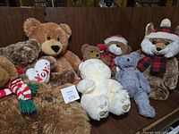 Front view of eight varied stuffed bears with some Christmas accessories and scarves, showing size and condition.