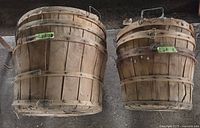 Two wooden bushel baskets side by side showing exterior slat construction and wire handles