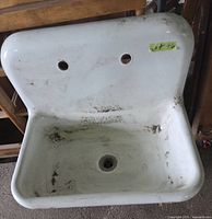 front view of white enamel wall mount sink with two faucet holes and drain