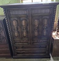 Front exterior of dark wood armoire with doors and drawers closed
