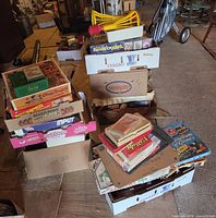 Two cartons holding stacked boxed board games and puzzles