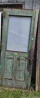 Full view of darker green side of door showing smoked glass, panels, hinges, handle, chain and lock