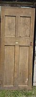 Full front view of wooden 4-panel door showing hinge and mortise