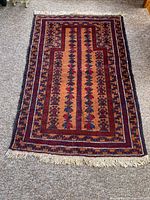 Full view of rectangular Baluch prayer rug revealing overall geometric and floral pattern and fringe wear on one edge.