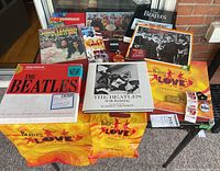 Overview of Beatles memorabilia arrayed on floor including books, magazines, Beatles Love merchandise and pins