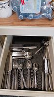 Opened drawer showing organized silver cutlery with knives and forks on left and spoons on right