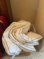 Folded white down filled bedding with black piping, showing softness and shape