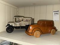 Wooden car and cast iron IM MacDonald produce delivery truck displayed on shelf.