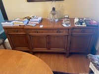 Full front view of walnut buffet with items on top.