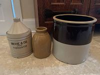 Photo showing all three items: crock pot, jug, and vase side by side on floor in front of furniture.